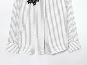 Detail of white striped cotton shirt featuring delicate black floral lace embroidery