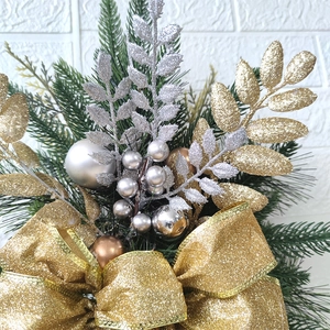 Close-up of Christmas stairs garland with gold pine needles, baubles, and a large bow