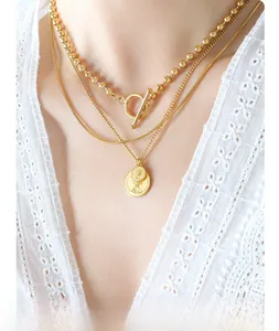 Detail of triple-layered gold coin necklace featuring vintage OT clasp and engraved charms