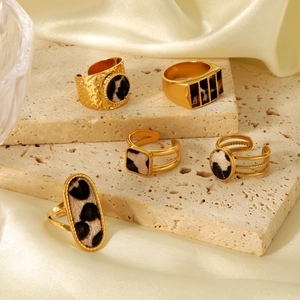 Detailed view of vintage gold leopard print rings on a textured stone display pedestal