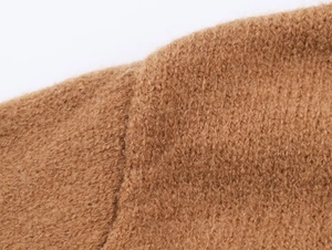 Gros plan de la texture en maille peluche marron et détails de couture sur le pull