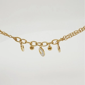 Detailed macro view of double-layered gold chain with zircon charms and bead pendants