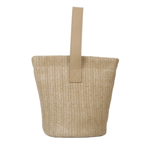 Minimalist straw bucket bag with leather handles and beige woven texture for summer