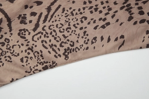 Gros plan sur un tissu en maille à imprimé léopard kaki et marron foncé avec détails