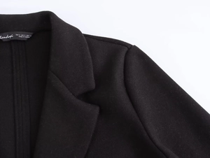 Close-up of black wool coat lapel and shoulder stitching with brand size tag details