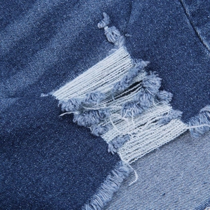Nahaufnahme der Distressed-Denim-Textur mit Rissen und offenen Kanten in Dunkelblau