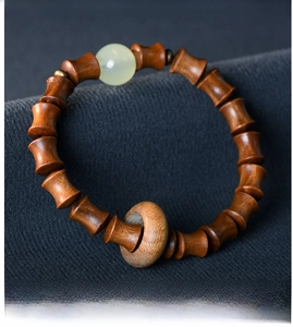 Detail of sandalwood bamboo joint bracelet with green jade bead and safe knot pendant