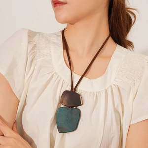 Detail of vintage long sweater necklace with irregular wooden and stone pendants