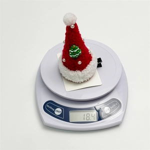 Detailed view of a plush Christmas hat hair clip on a digital scale weighing 18.4g