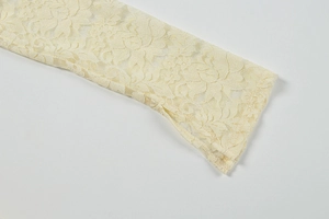Detailed close-up of delicate lace embroidery and split cuff on an ivory dress sleeve