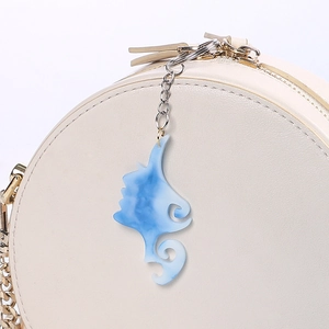 Close-up of blue marble acrylic keychain charm with elegant silhouette on a beige bag