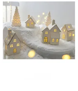 Details von weißen Keramik-Weihnachtshäusern mit warmer LED-Beleuchtung auf Schnee
