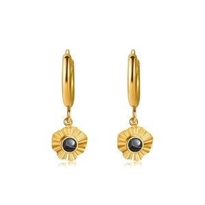 Detailed view of gold starburst earrings featuring black stone inlay and textured edges