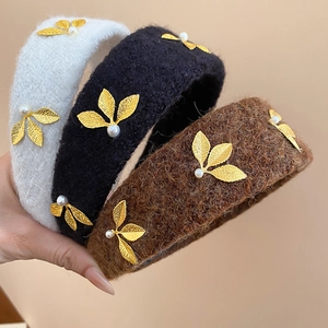 Detail of plush headbands with golden leaves and pearls in black, white and brown