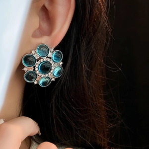 Close-up of vintage flower earrings with blue crystals and silver accents on model
