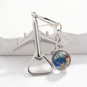 Silver metal airplane keychain bottle opener with a blue planet pendant on white blocks