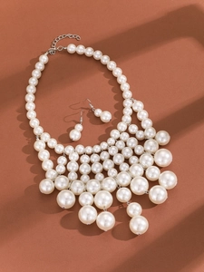 Detail of multi-layer pearl necklace and drop earrings set on brown background