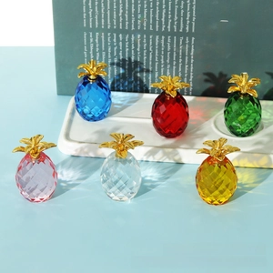 Close-up of colorful faceted crystal pineapple figurines with golden metal leaves