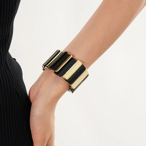 Detail of a fashion wide stretch bracelet with gold metal and black enamel geometric blocks