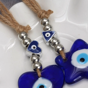 Macro shot of evil eye charms featuring blue heart and star shapes on hemp rope