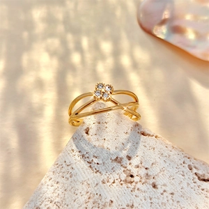 Detail of gold hollow crisscross ring with four-diamond cluster on white stone