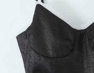 Détail du tissu texturé noir avec volants en tulle blanc sur l'encolure de la robe