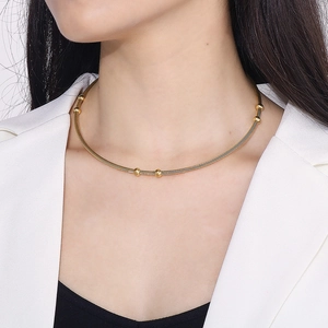 Detail of gold cable choker necklace with three metallic beads on a female model