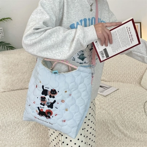 Detailed close-up of light blue quilted tote with cute cat embroidery and pink strap