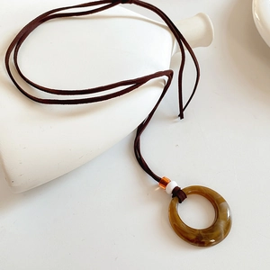 Detailed close-up of a vintage resin round pendant on a brown suede cord necklace