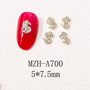 Detailed close-up of gold dollar sign nail art charm with rhinestones on a red nail