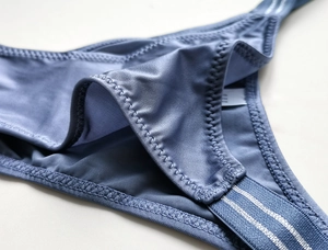 Close-up of smooth blue satin fabric and silver striped elastic waistband detail