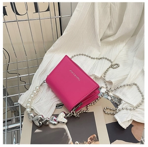 Detail of rose red crossbody bag with silver beaded chain and pearl heart charm