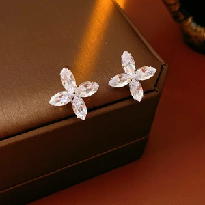 Vue macro de boucles d'oreilles trèfle en argent et zircons sur un coffret à bijoux luxe
