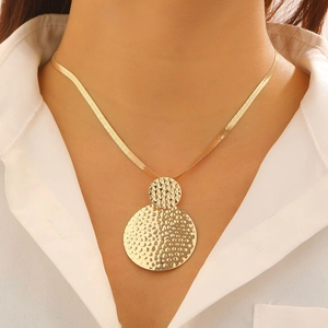 Detail of golden hammered double disc pendant on a sleek herringbone chain necklace