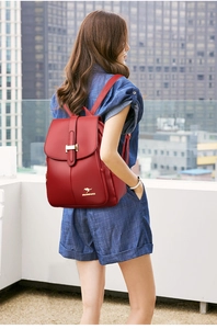 Detail of red leather backpack featuring metal H-buckle and golden kangaroo logo