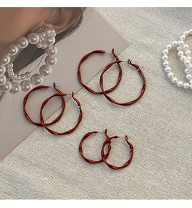 Detailed view of three pairs of dark red twisted hoop earrings in vintage style