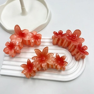 Dettaglio di tre mollette per capelli a forma di fiore di frangipane arancione su vassoio