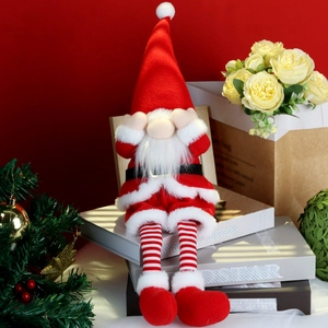 Detail of Christmas gnome plush doll with long striped legs sitting on vintage books