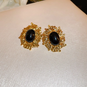 Detailed macro view of vintage gold leaf earrings with oval black center stone inlay
