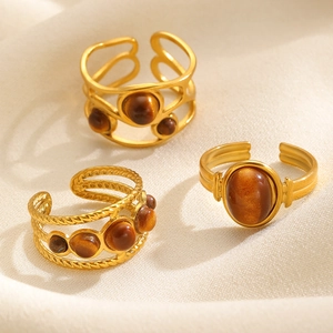 Detailed view of gold stainless steel open rings with tiger eye and pearl insets