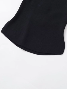 Close-up of the black knit fabric texture and hemline finish of the backless top