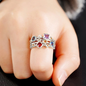 Detalle de anillos plateados de varias capas con piedras preciosas geométricas