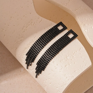 Détail de boucles d'oreilles à pompons noirs en zircon avec design géométrique évidé