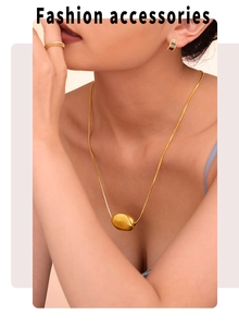 Detail of gold bean pendant necklace paired with colorful gemstone earrings and ring