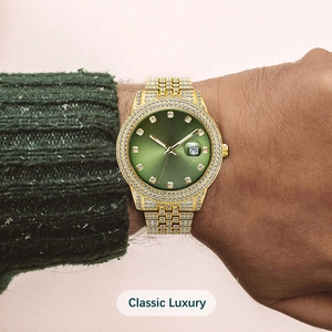 Close-up of iced out gold watch with green sunray dial and calendar display