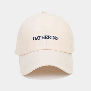 Close-up of GATHERING embroidery and navy stitching on off-white cotton baseball cap