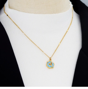 Detail of blue enamel irregular round pendant with gold fishtail on a beaded chain
