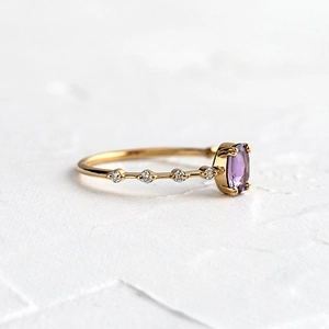 Macro view of 18k gold ring with oval purple gemstone and sparkling side stones