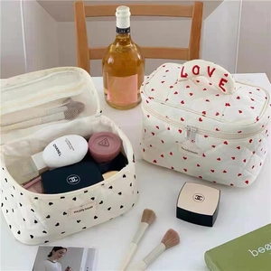 Detail of open quilted makeup bag showing internal storage with heart pattern