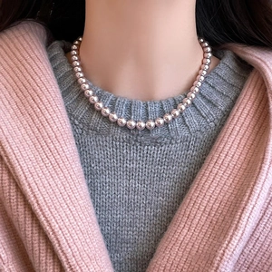 Close-up of pink-purple pearl necklace on model wearing a soft knit cardigan
